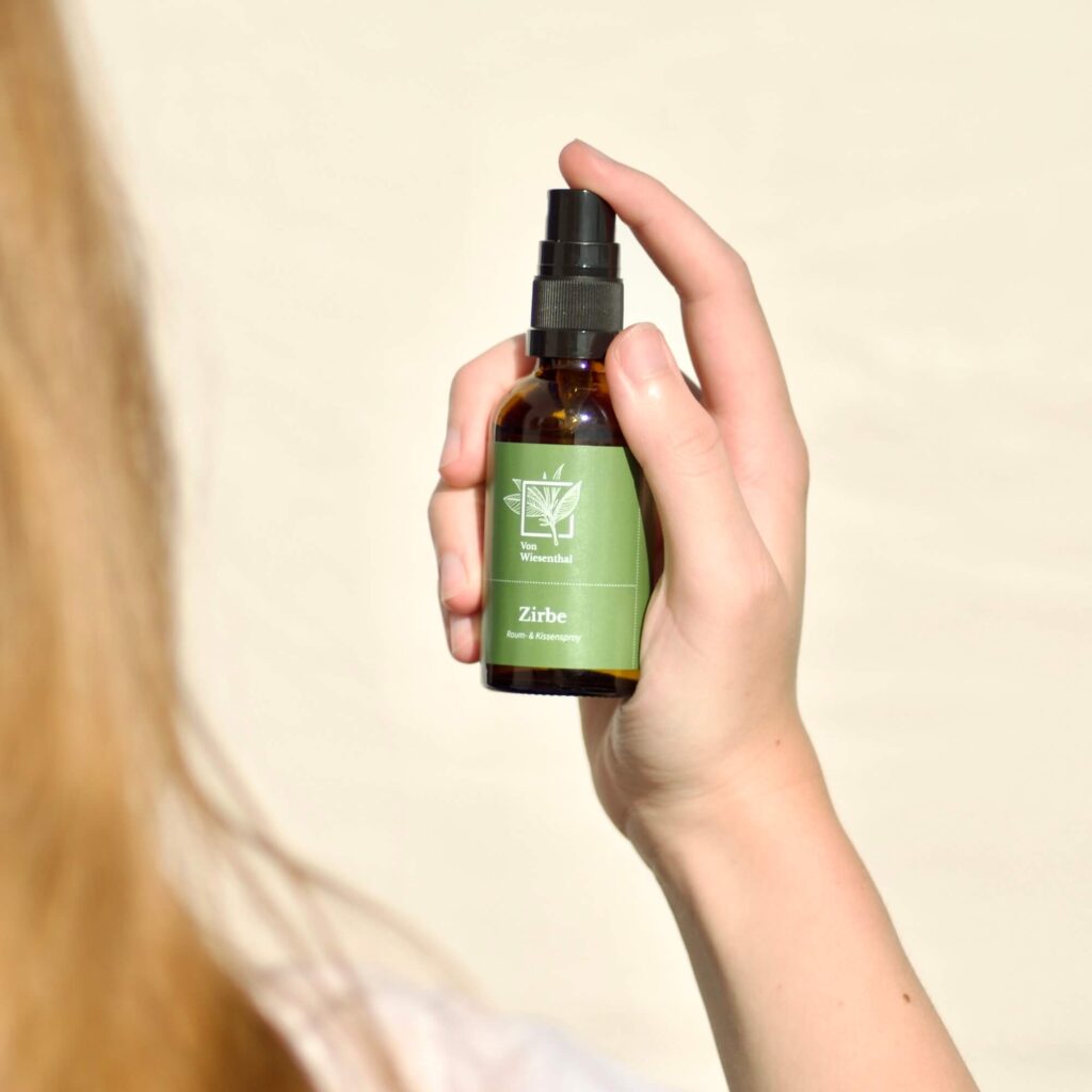 Eine Frau sprüht mit dem alpinen Zirben Raum- und Kissenspray