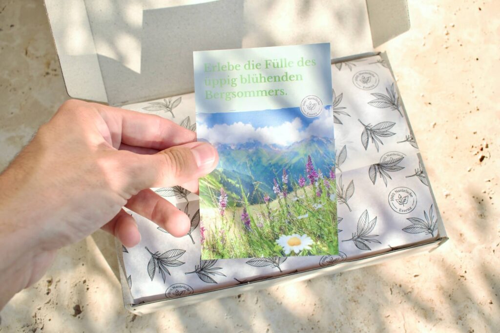 Ein Mann legt einem Paket mit dem naturreinen ätherischen Duftöl Almwiese eine handgeschriebene Grußkarte bei
