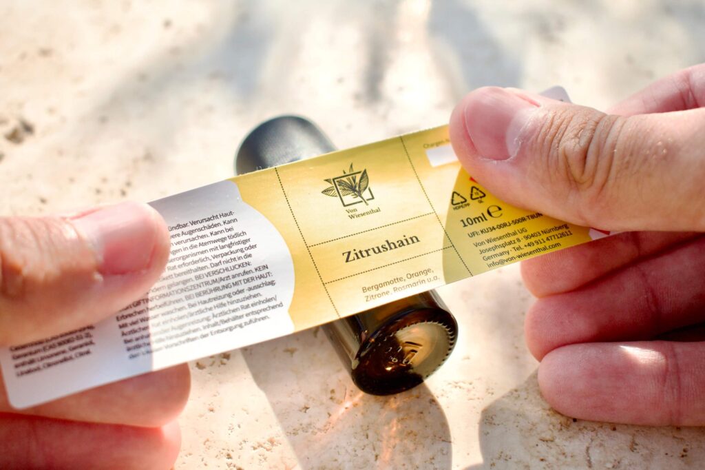 Ein Fläschchen des mediterranen Duftöls Zitrushain wird in der Manufaktur etikettiert