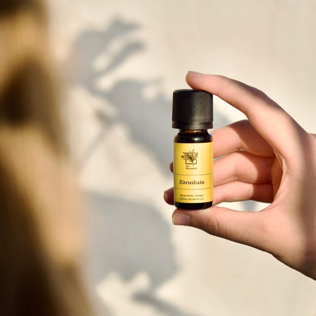 Eine Frau hält eine Flasche des Raumdufts Zitrushain in die Sonne